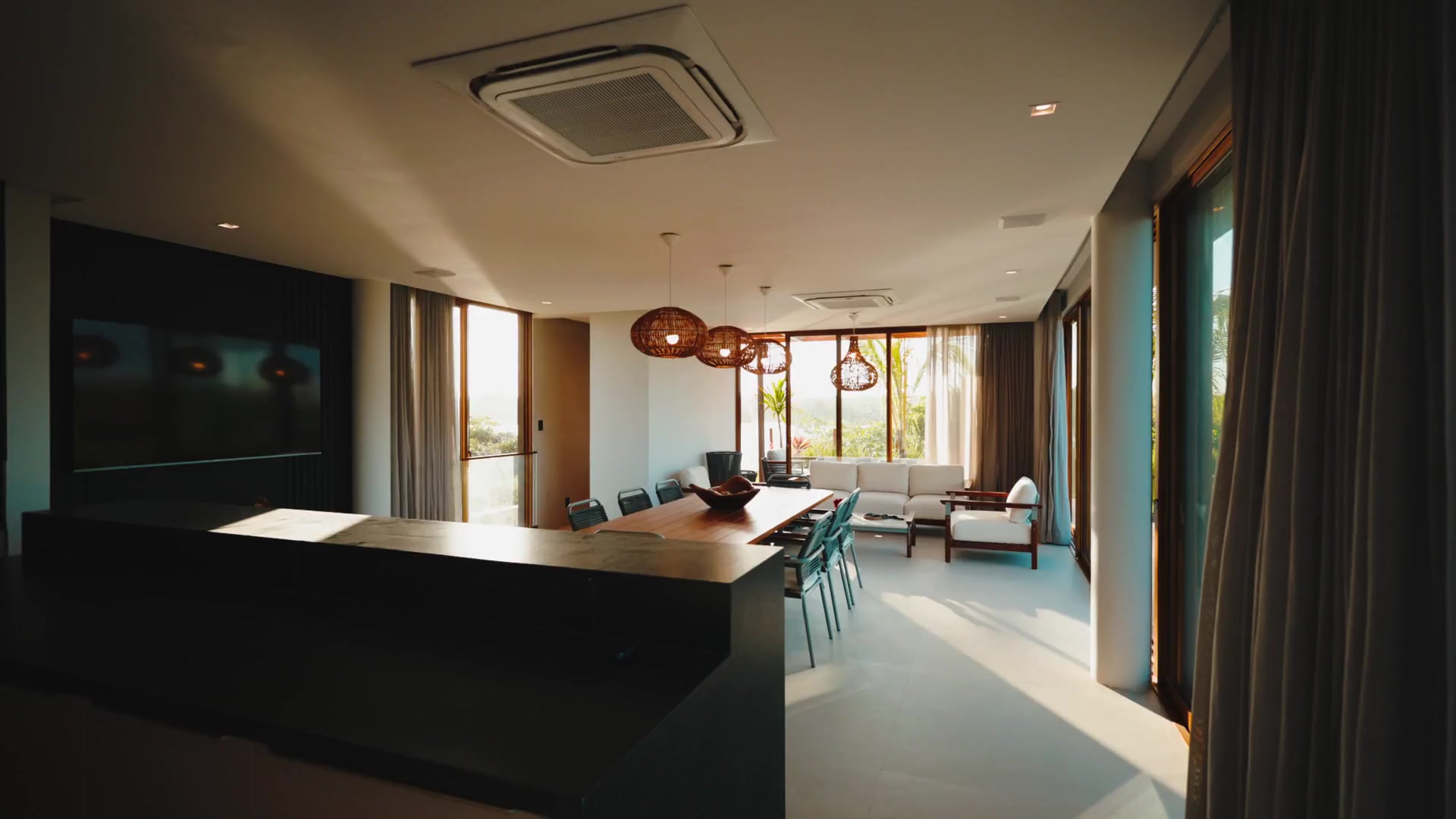 Open living and dining space with timber table and woven pendant lights